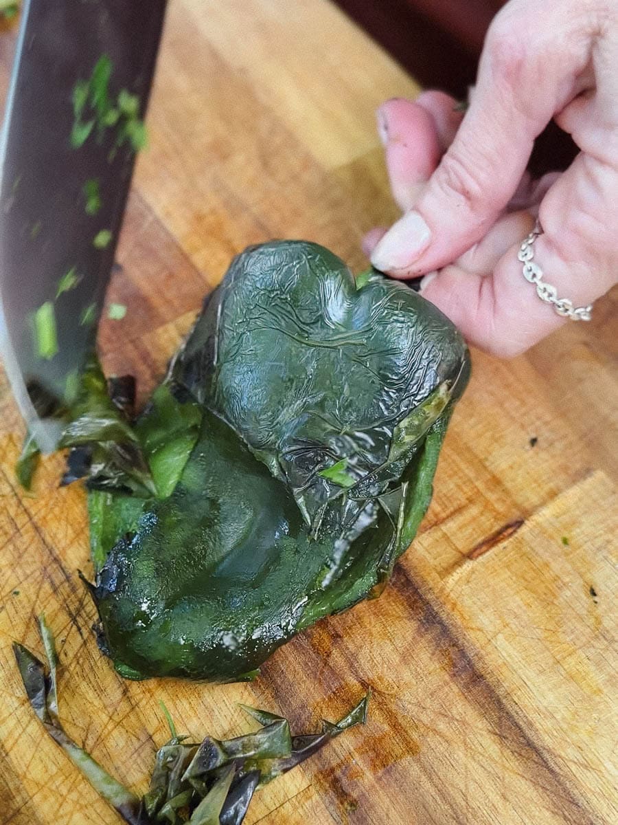 main qui retire la peau d'un piment poblano