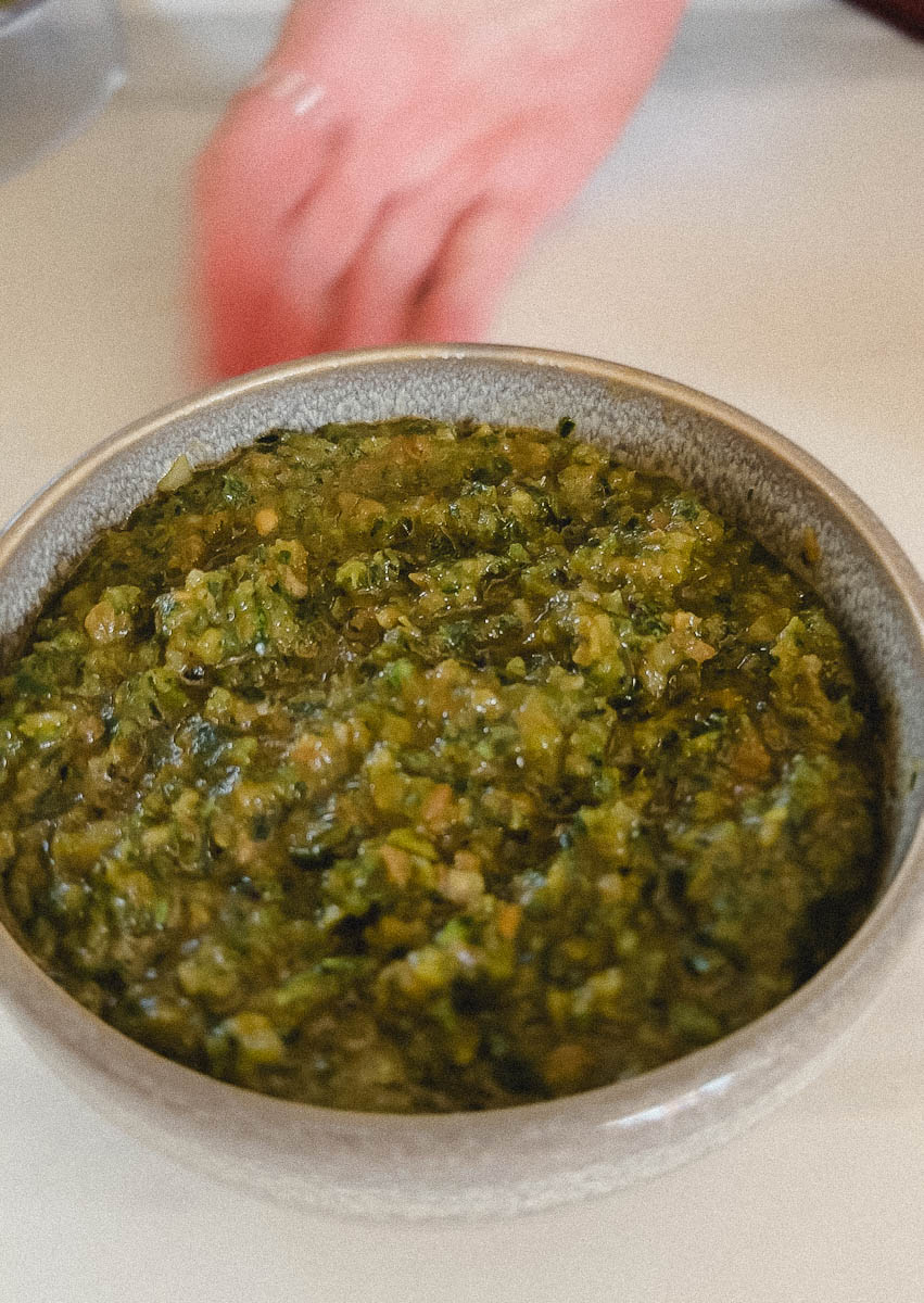 main qui présente bol de sauce chimichurri