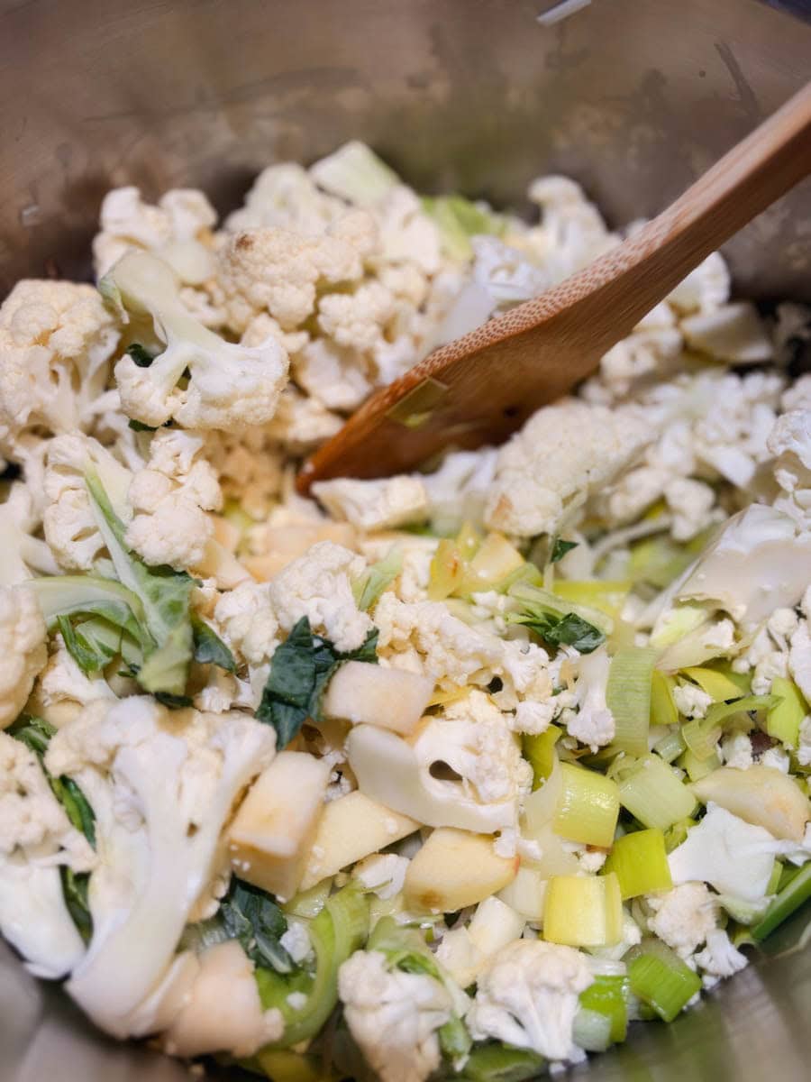 légumes pour crème de poireaux qui cuisent dans casserole avec cuillère en bois