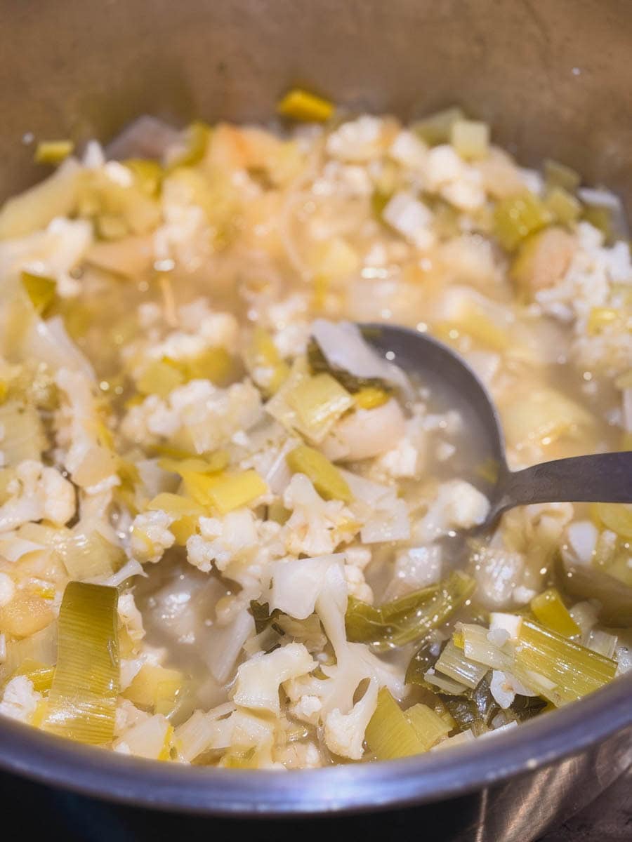 légumes pour crème de poireaux qui cuits dans casserole avec cuillère en bois