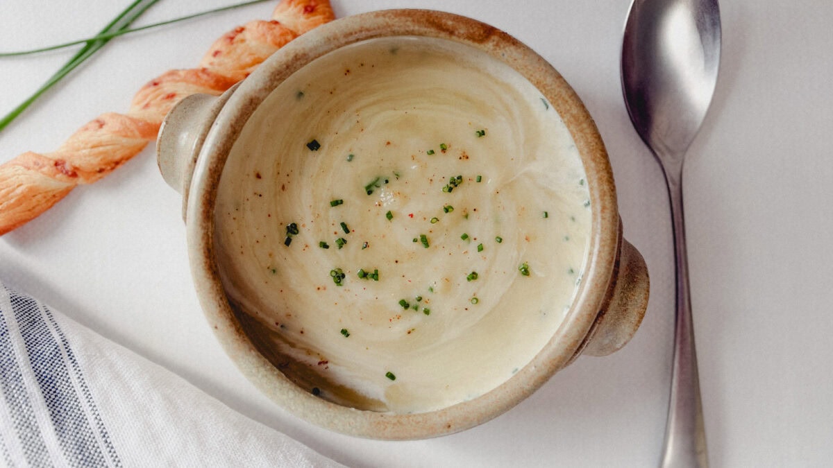bol de crème de poireaux veloutée avec cuillère,paille au fromage et quelques brins de ciboulette