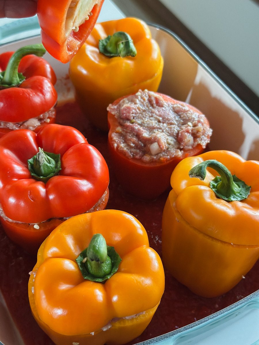 6 poivrons farcis dont un où on voit la farce et main qui dépose le chapeau du poivron