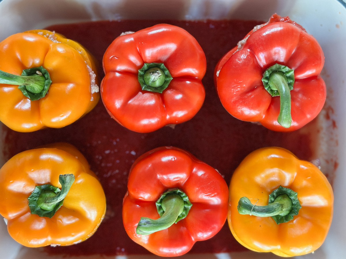 6 poivrons farcis dans un plat à gratin avec sauce tomate au fond
