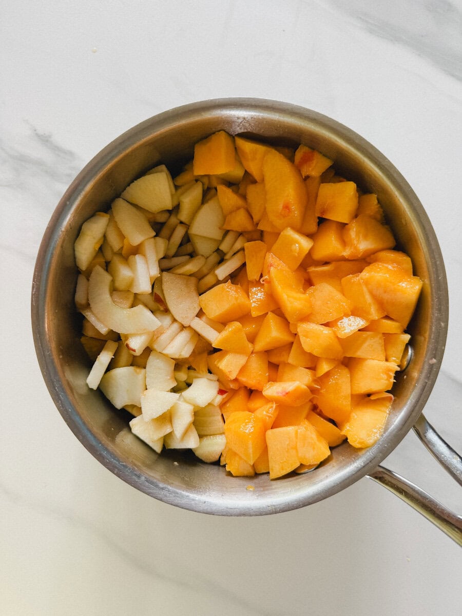 casserole avec moitié dés de pêche et moitié dés de pommes sur comptoir blanc marbré