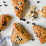 4 gros scones aux bleuets avec bleuets sur comptoir pâte avec linge blanc et bleu en lin