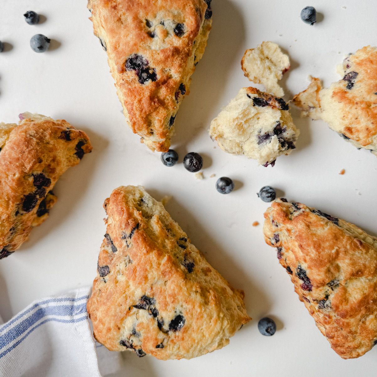 4 gros scones aux bleuets avec bleuets sur comptoir pâte avec linge blanc et bleu en lin