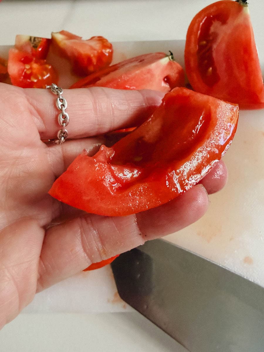 main qui montre l'intérieur d'un quartier de tomate