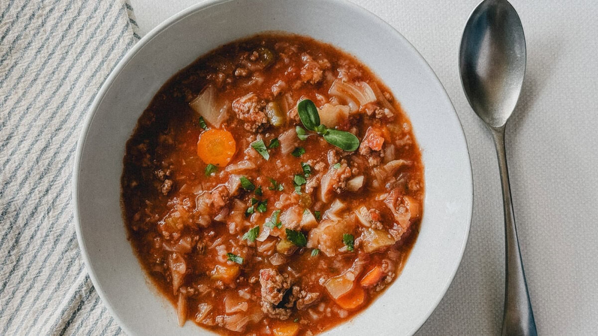 soupe style cigare au chou dans un bol blanc avec cuillère et linge de table à côté