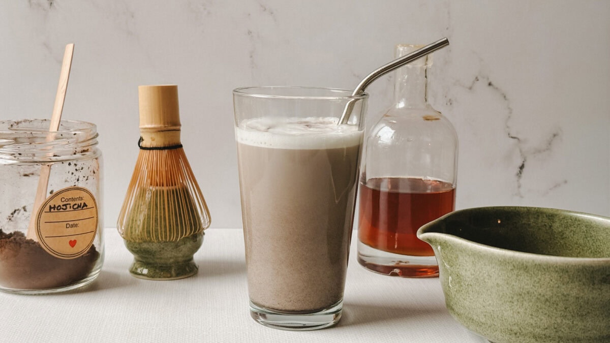 Latte au hojicha servi dans un verre avec paille en inox