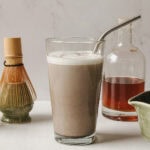 Latte au hojicha servi dans un verre avec paille en inox sur fond marbré