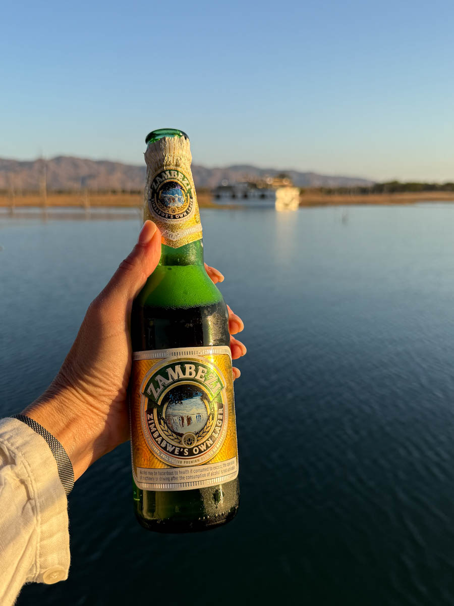 main qui tient Biere zambezi devant bateau