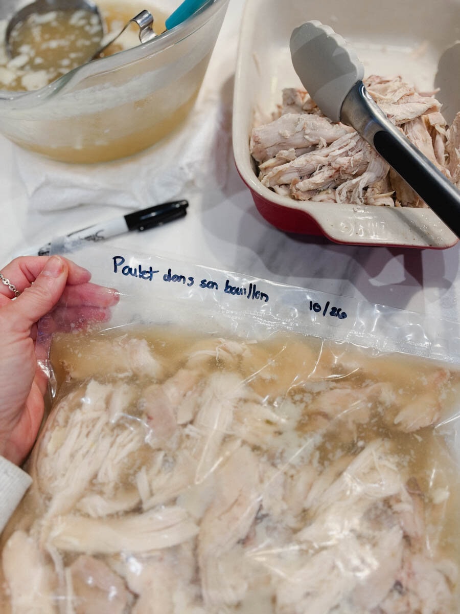 main qui tient un sac de poulet effiloché dans son bouillon écrit poulet dans son bouillon