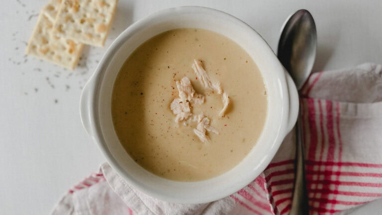 bol de crème de poulet garni de poulet en morceaux, avec biscuits soda, linge de table et cuillère