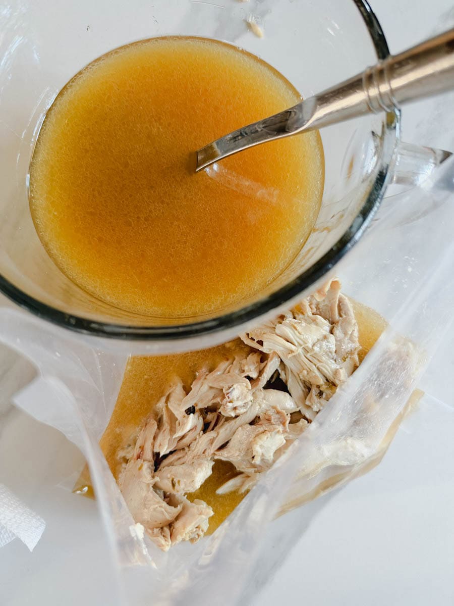 bouillon de poulet dans contenant avec louche et sac de viande de poulet cuite couverte de bouillon
