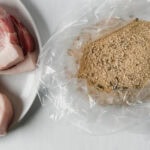 chapelure shake and bake maison étalée dans un sac de plastique ouvert, à côté de côtelettes de porc crues dans une assiette blanche
