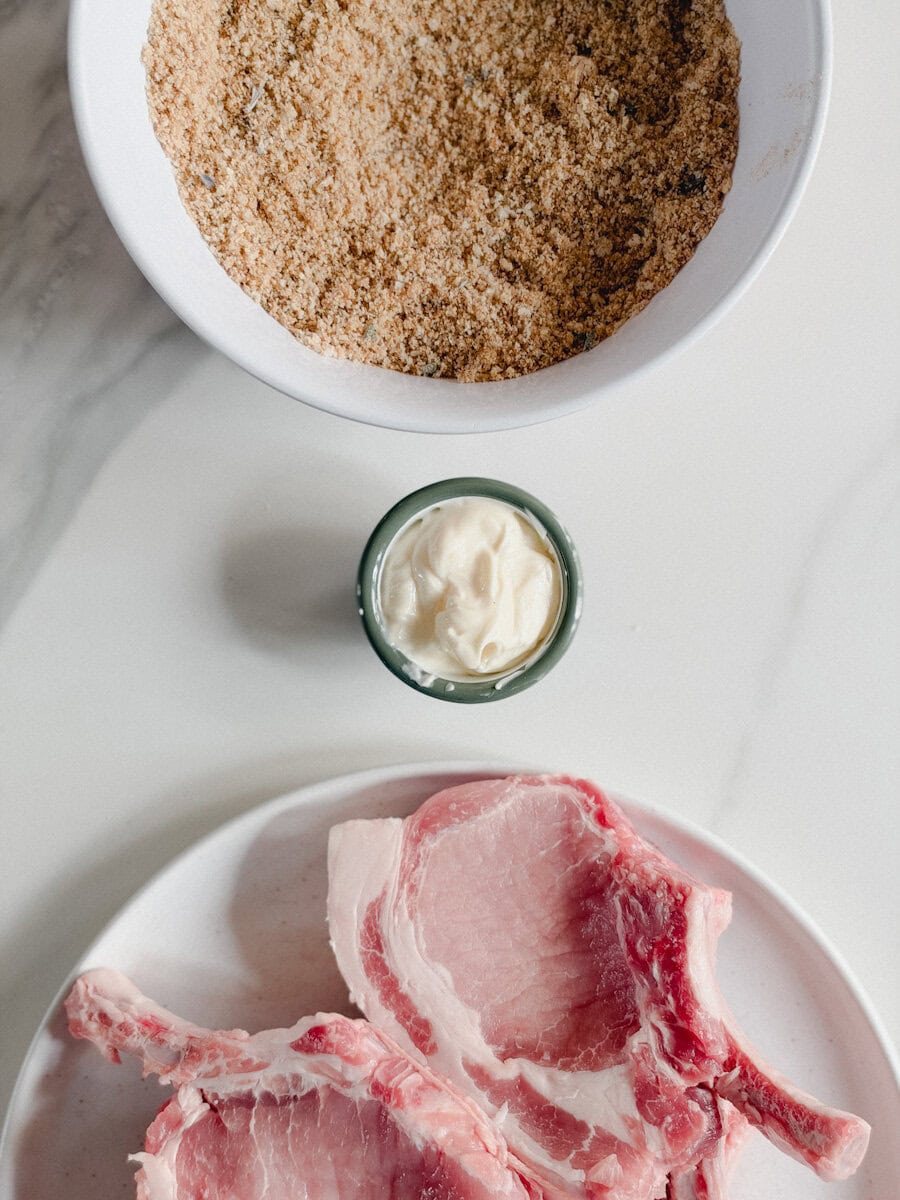côtelettes de porc dans une assiette, bol de mayonnaise et autre bol de chapelure