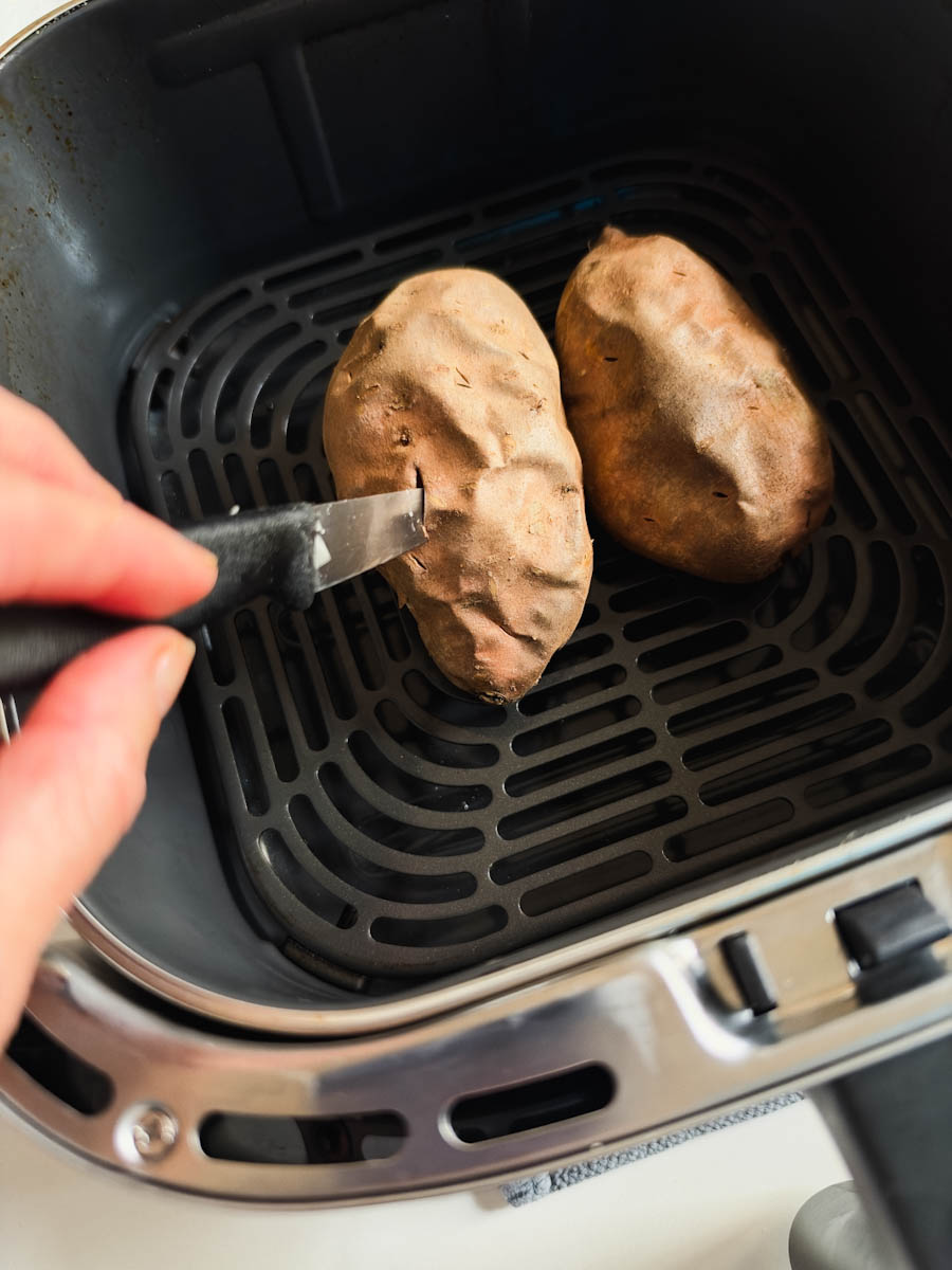 main tenant couteau qui teste cuisson de patate douce dans air fryer