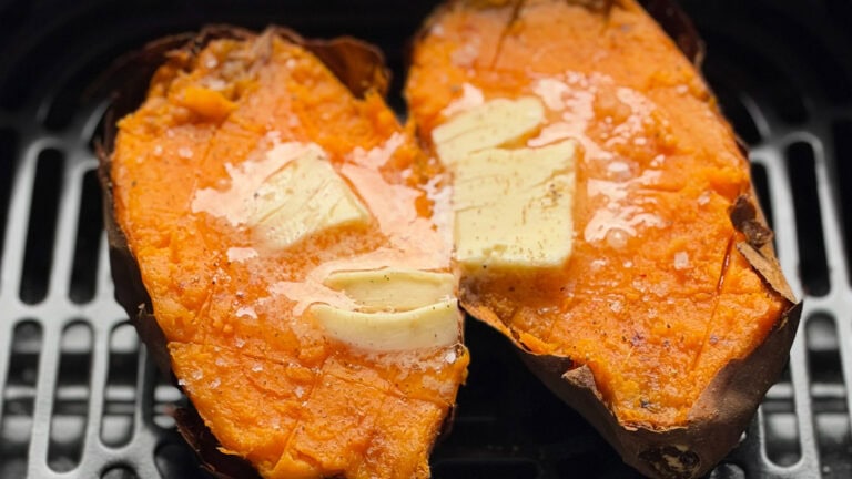 patate douce ouverte en deux, carré de beurre qui fond sur chaque moitié dans panier sur grille du air fryer