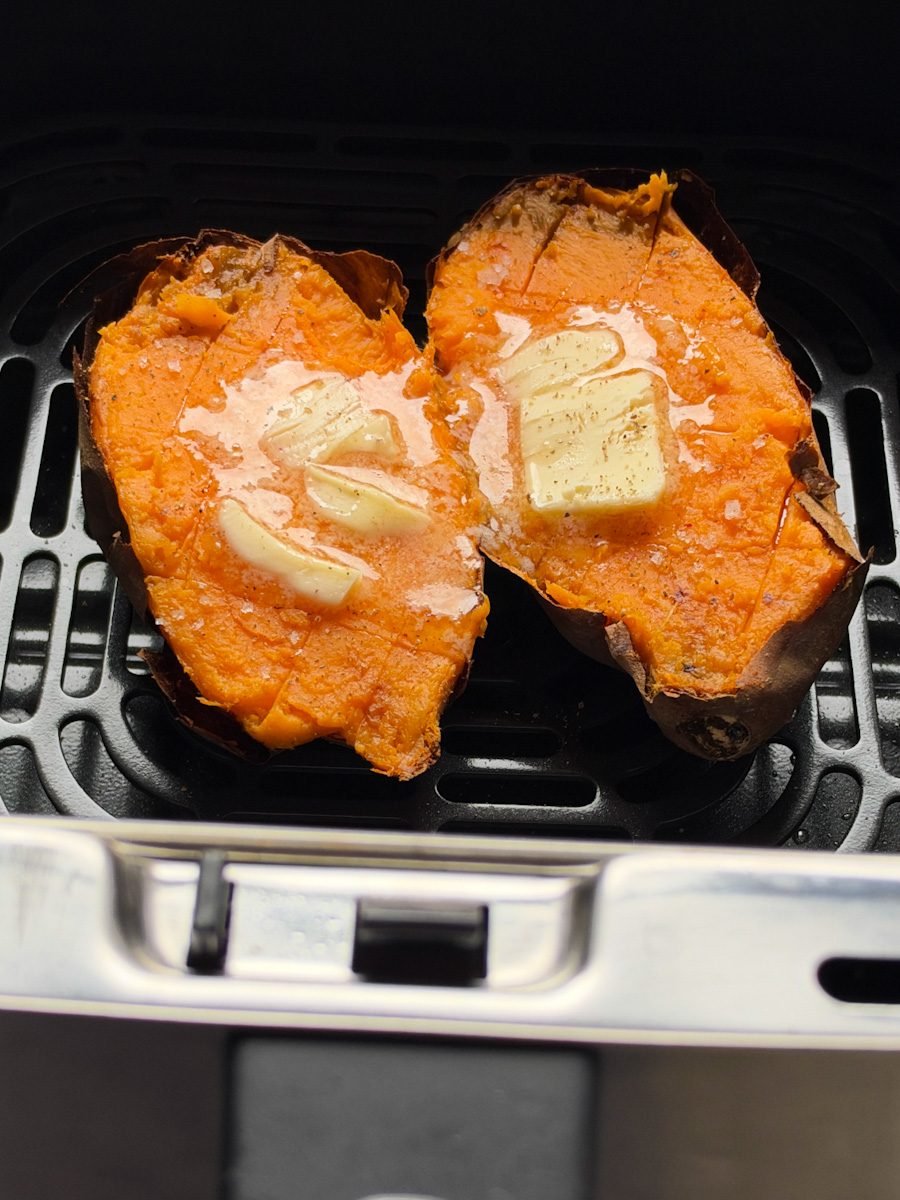 patate douce ouverte dans le panier du air fryer avec beurre qiui fond sur le dessus