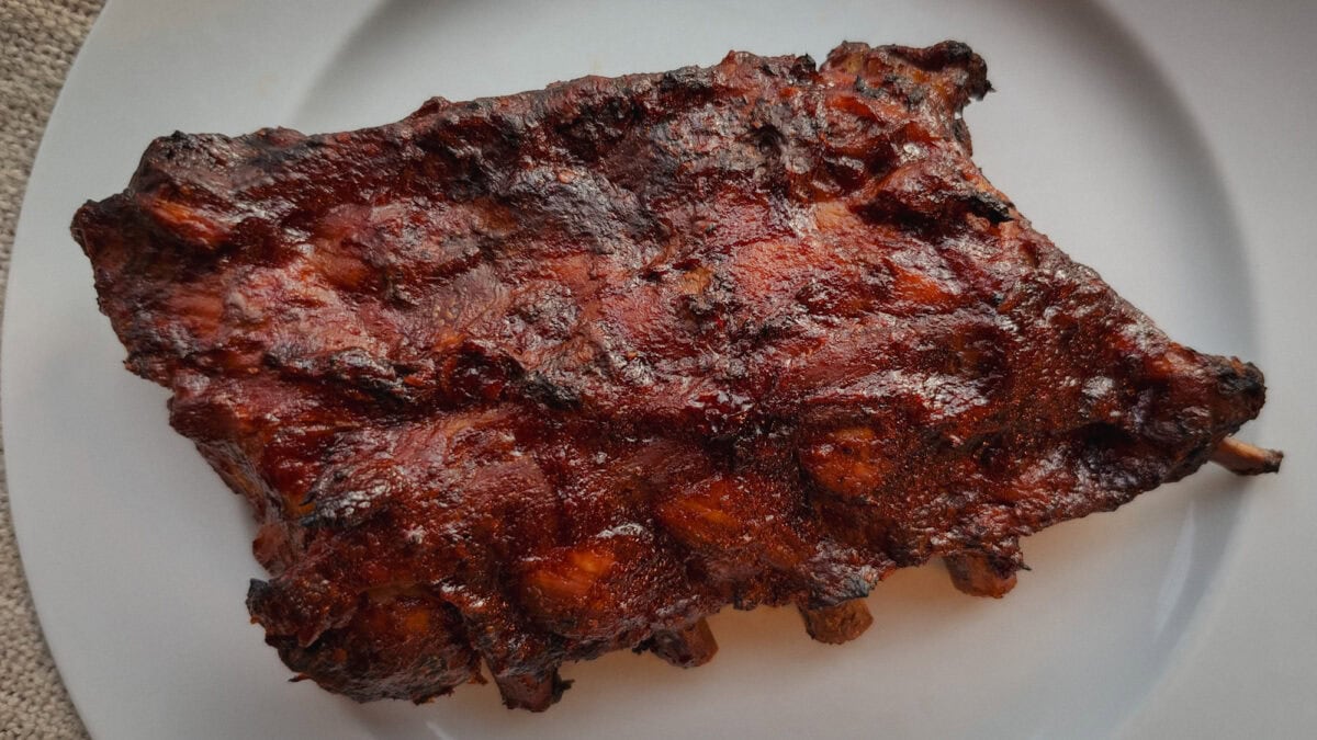 Demi-rack de côtes levées de dos laquées de sauce BBQ, braisées à la mijoteuse et grillées au air fryer, servies dans une assiette blanche