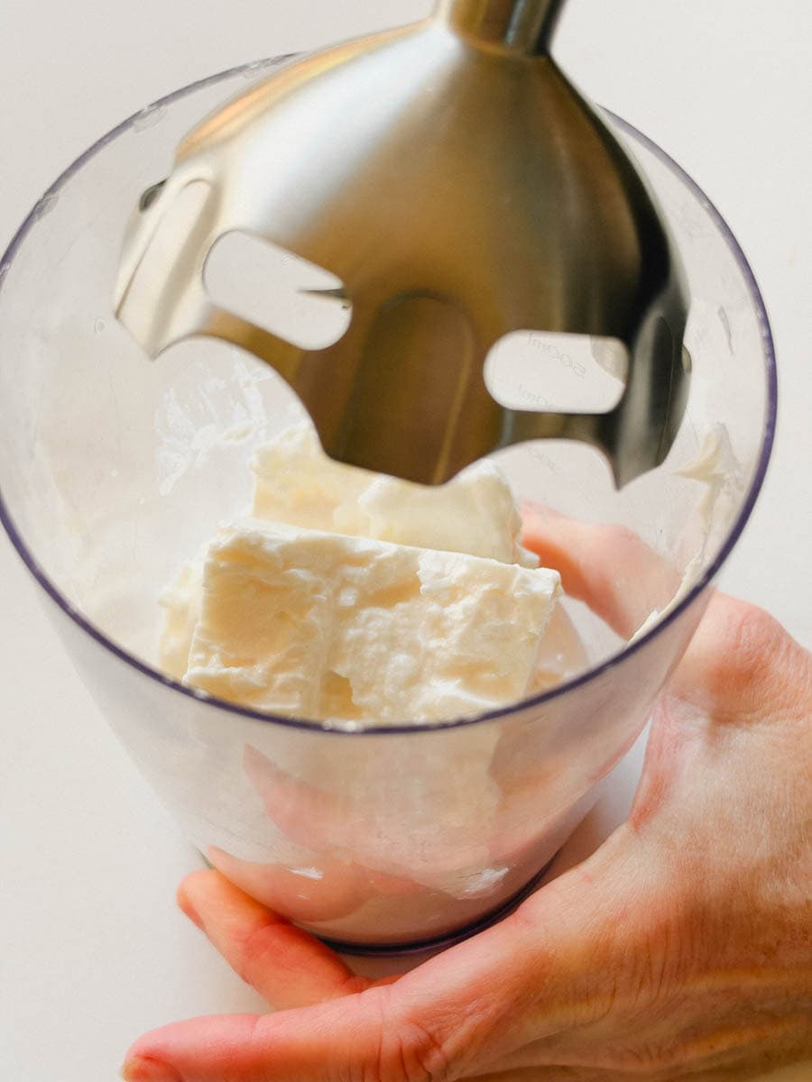 pied mélangeur inséré dans bol avec ingrédients pour tartinade feta fouetté