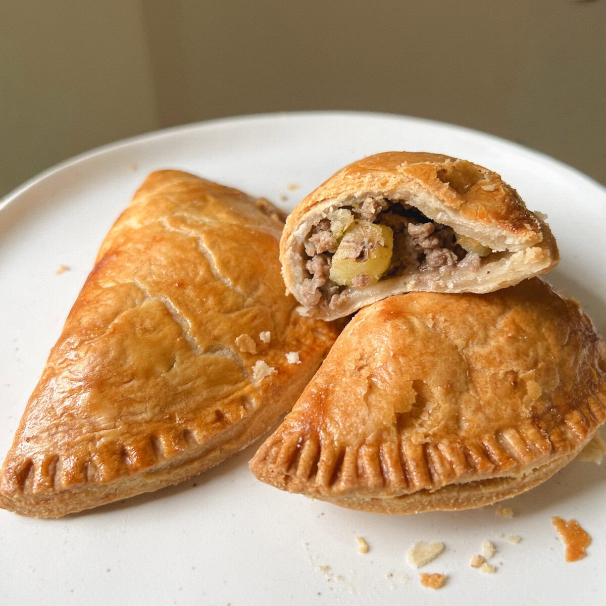 chausson tourtière à la pâte dorée dont moité montrant pomme de terre et boeuf haché