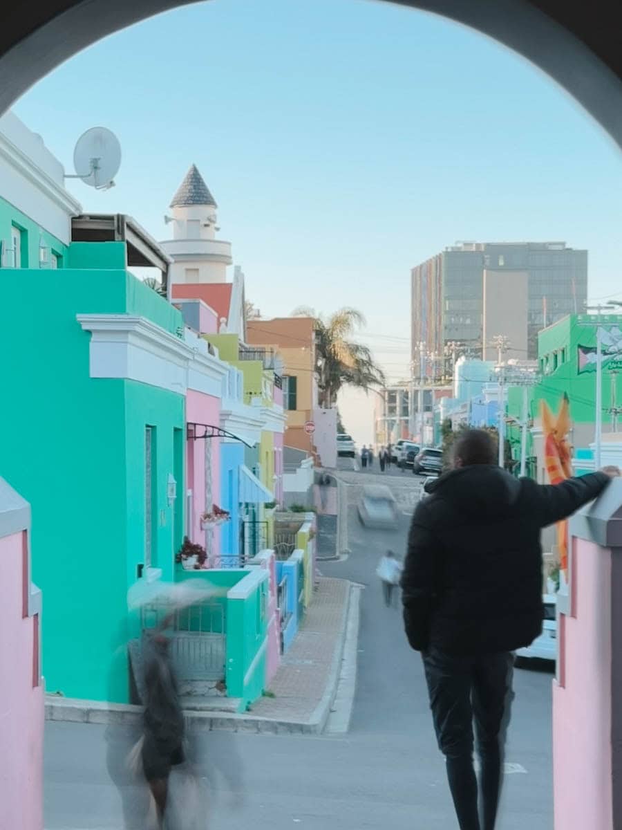 homme sous une arche regardant la vue des maisons colorées de bo-kaap